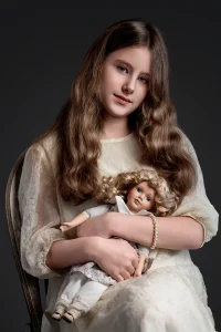 Girl with wavy hair holding a vintage doll in artistic portrait by Chaplin Studio