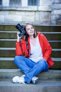 Lidia Chaplin, professional photographer, seated on stone steps holding her camera