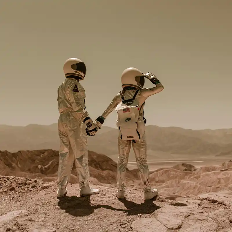 Two individuals in astronaut suits standing on a Mars-like surface, conceptual sci-fi image