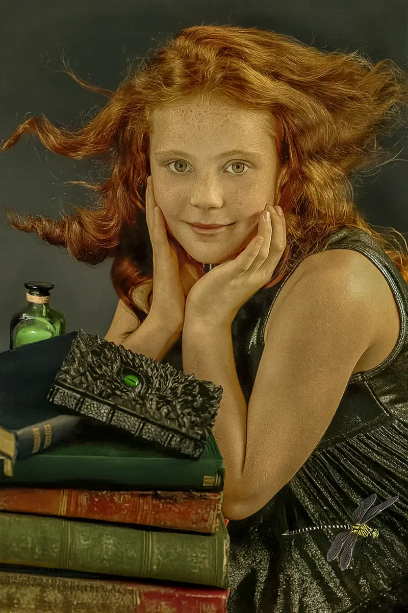 Artistic portrait of a girl with ginger hair and freckles, surrounded by books, by Chaplin Studio in Yorkshire.