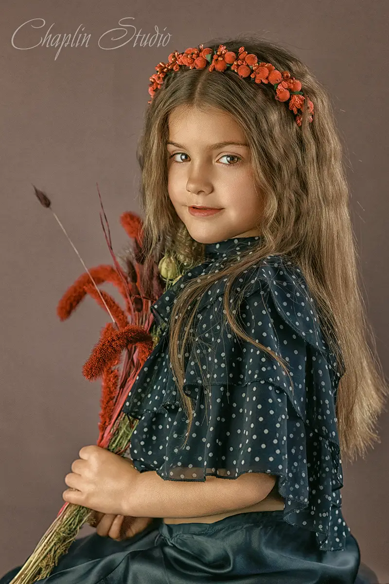 Fine art children's portrait of a girl with long hair, wearing a flower crown and holding dried flowers – styled photography by Chaplin Studio.