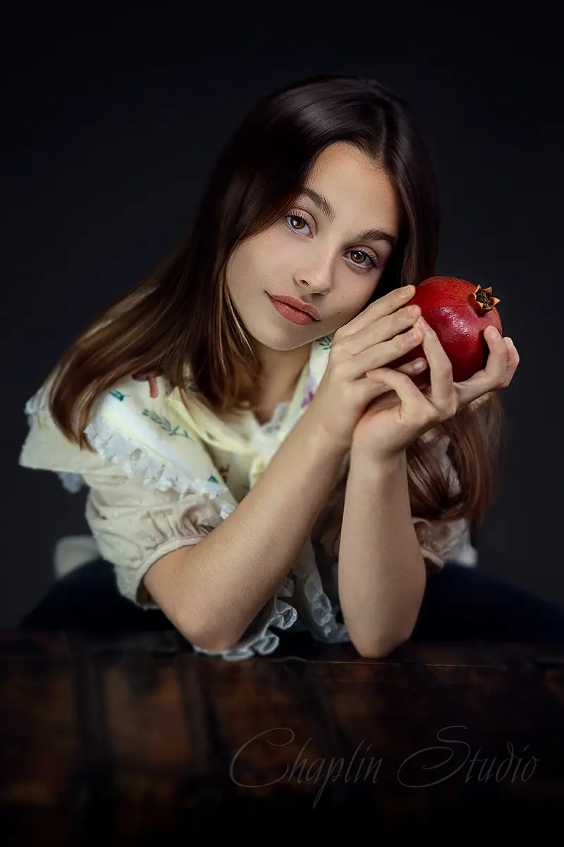 Fine art portrait of a young girl holding a pomegranate – children’s photography by Chaplin Studio, UK