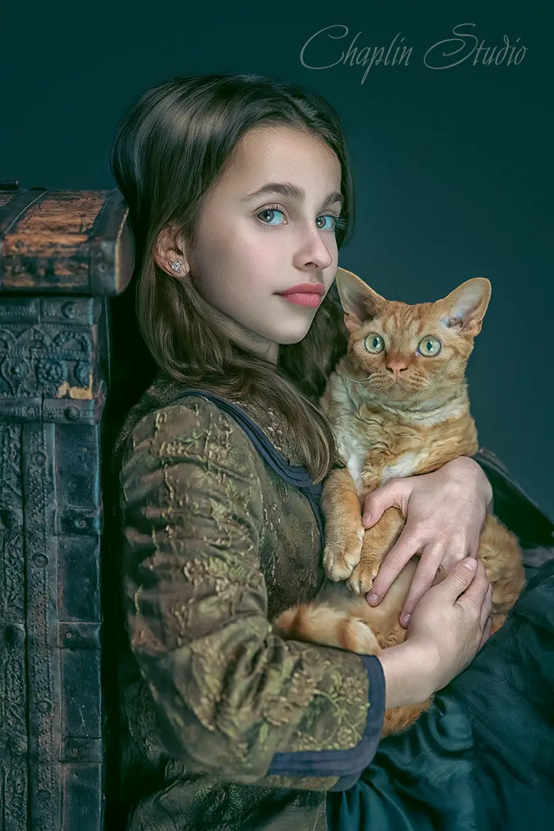 A fine art portrait of a young person holding a ginger cat, with a vintage chest beside them, captured by Chaplin Studio in Yorkshire.