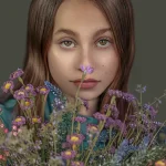 A captivating studio portrait of a young person with long hair, holding a bouquet of purple and yellow wildflowers, captured by Chaplin Studio in Yorkshire.