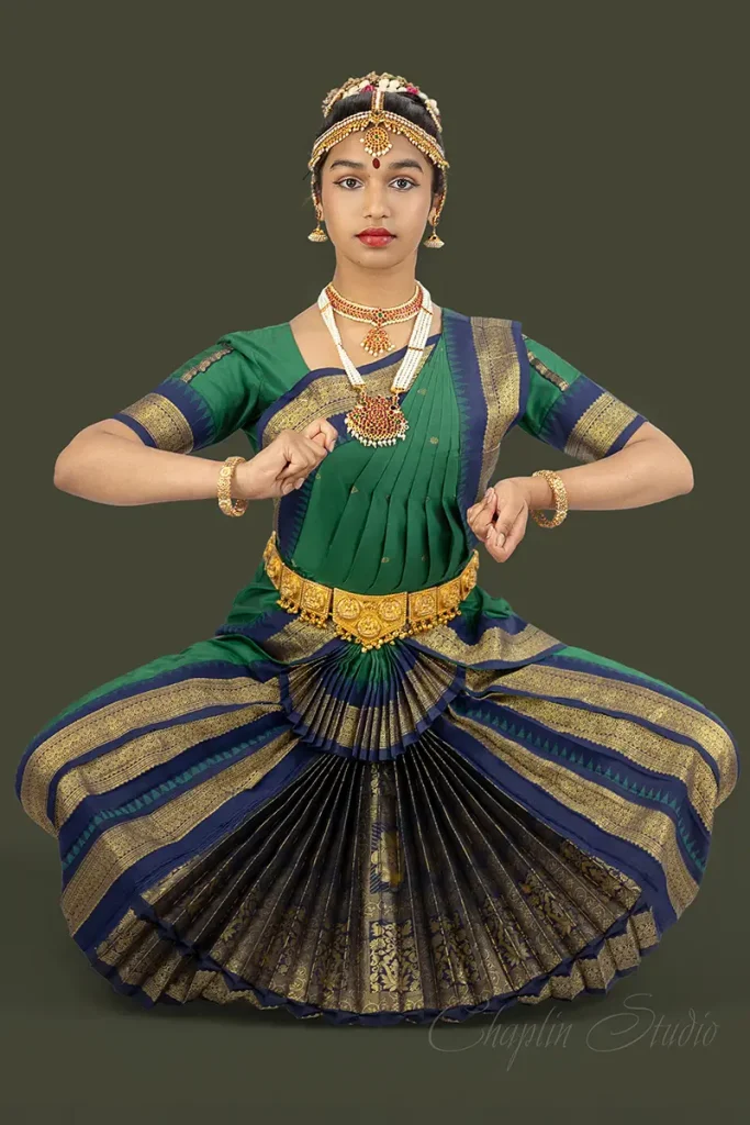 Portrait of a young woman in traditional Bharatanatyam dance costume, beautifully posed in classical Indian dance posture — studio photo by Chaplin Studio