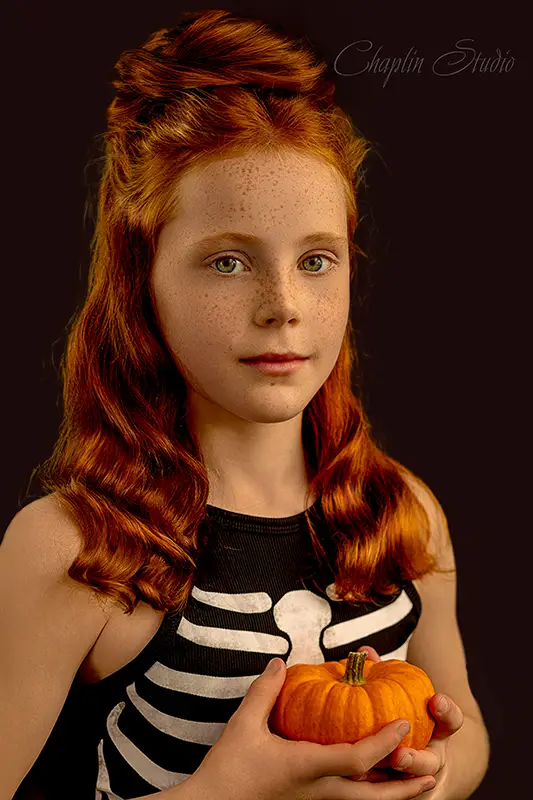 Red-haired girl holding a pumpkin in a Halloween costume during a children’s portrait session at Chaplin Studio Yorkshire